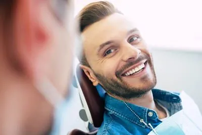 man laughing with his dentist after a dental crown helped restore his smile