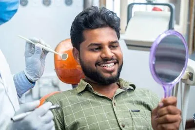 patient looking in the mirror at his new dental veneers