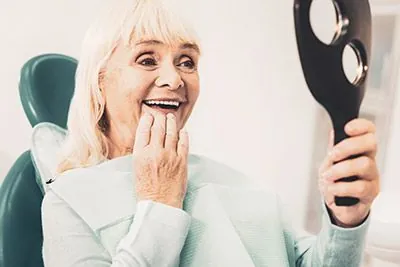 "teeth in a day" patient looking in the mirror at her restored smile