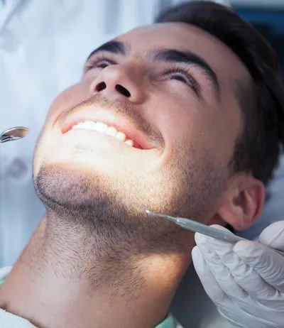 patient smiling while getting his teeth checked at Prosthodontic Associates of New Jersey