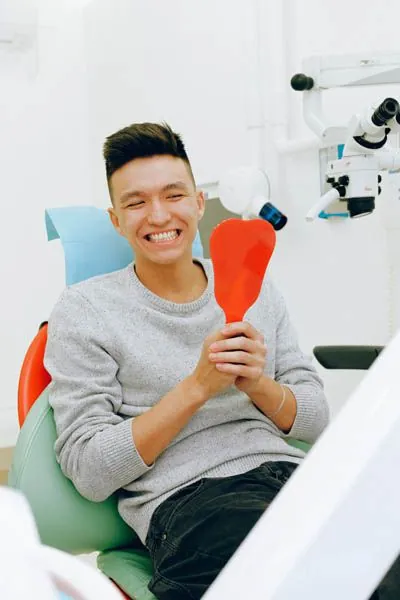 patient smiling while looking in the mirror after his dental cleaning